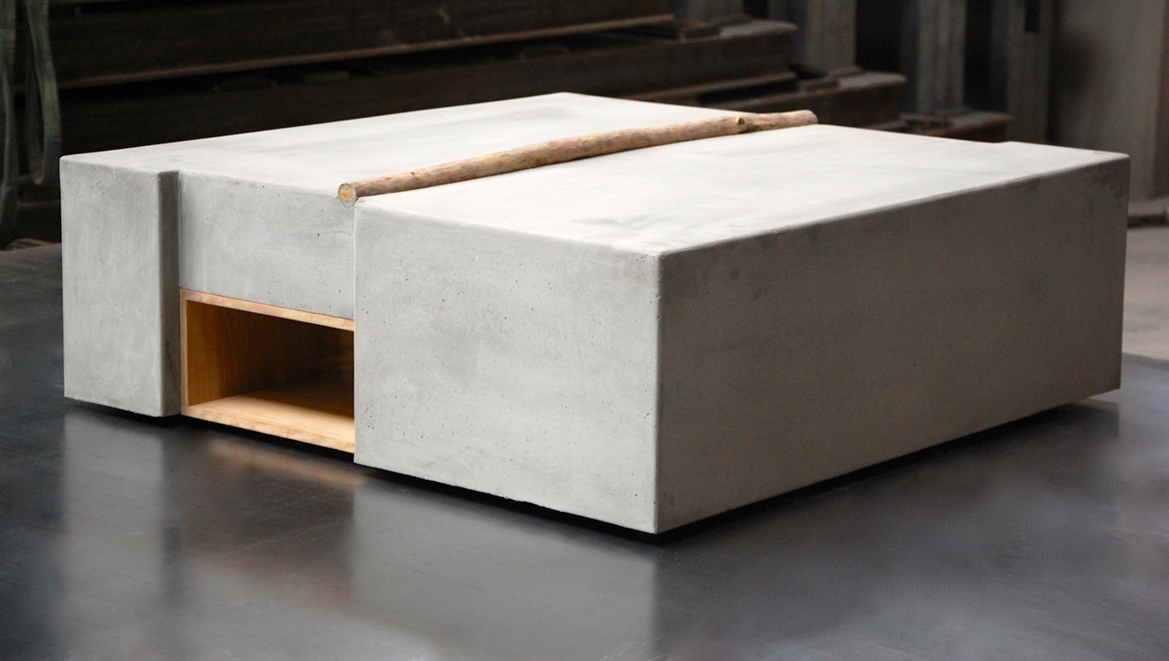 Kaffebord for stue som er laget av betong og har en liten oppbevaringsplass på en side